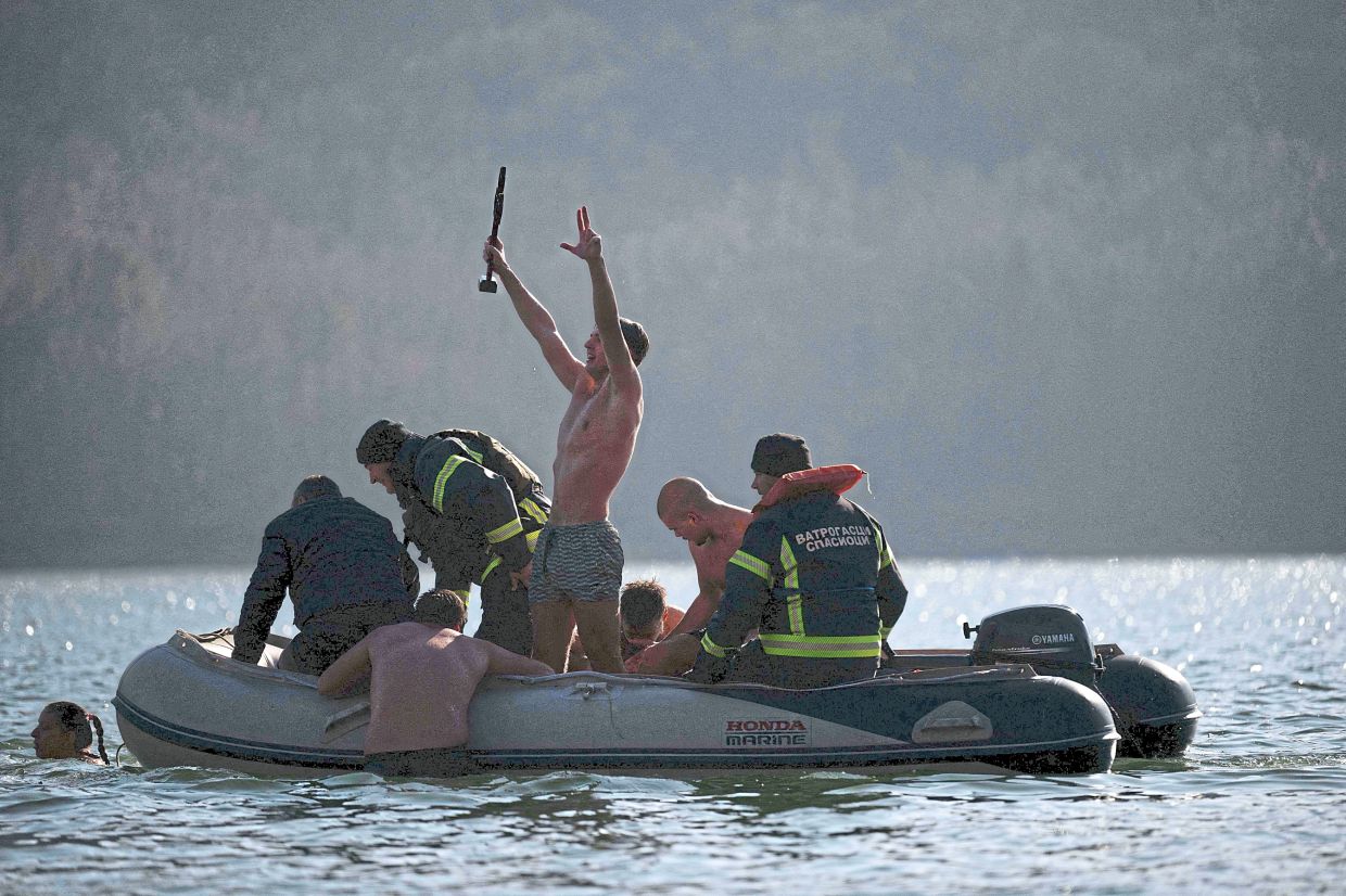 6. A man celebrating on a boat after retrieving a wooden cross thrown into the waters of Gazivoda Lake duringa traditional epiphany procession near Zubin Potok, north of Mitrovica, Kosovo. — AFP
