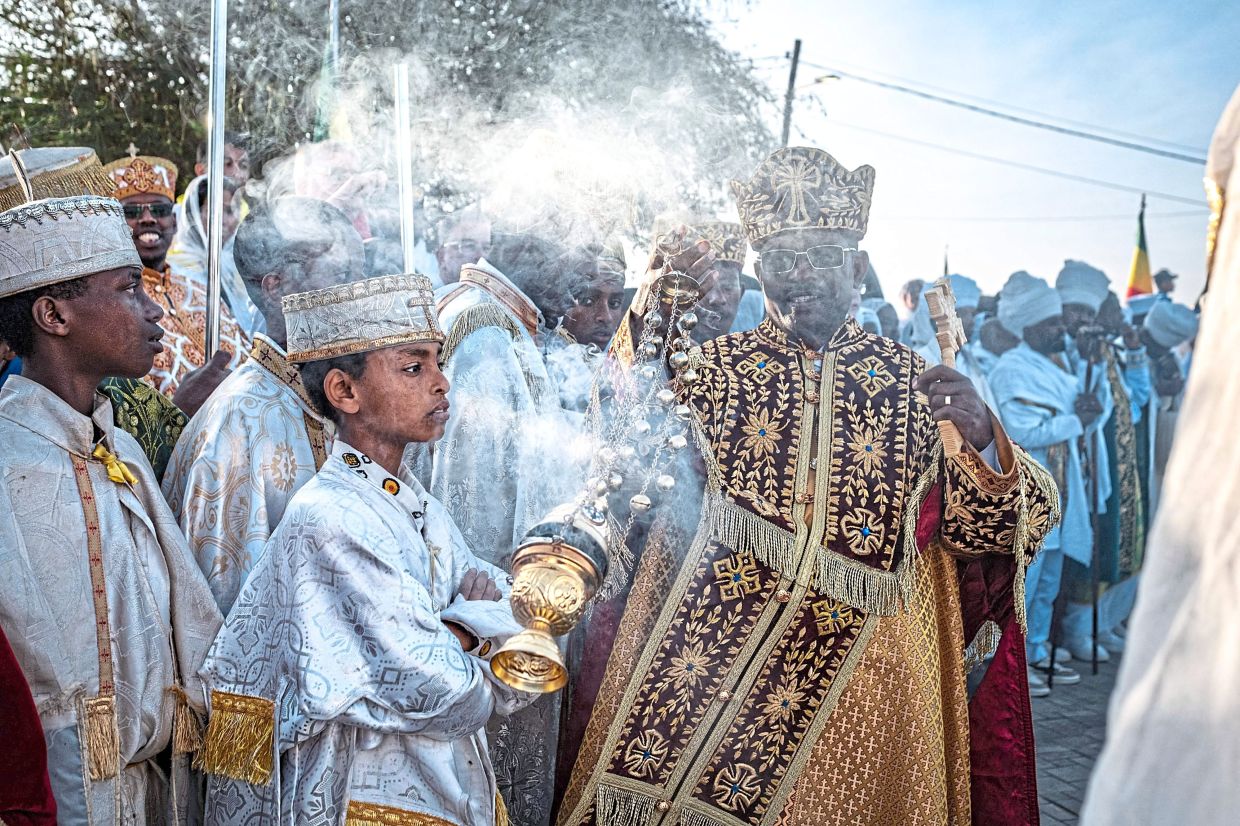3. A senior Orthodox cleric swinging a thurible, spreading incense among worshippers gathered around aceremonial pool during Timkat celebrations in Jan Meda, addis ababa, ethiopia. — AFP