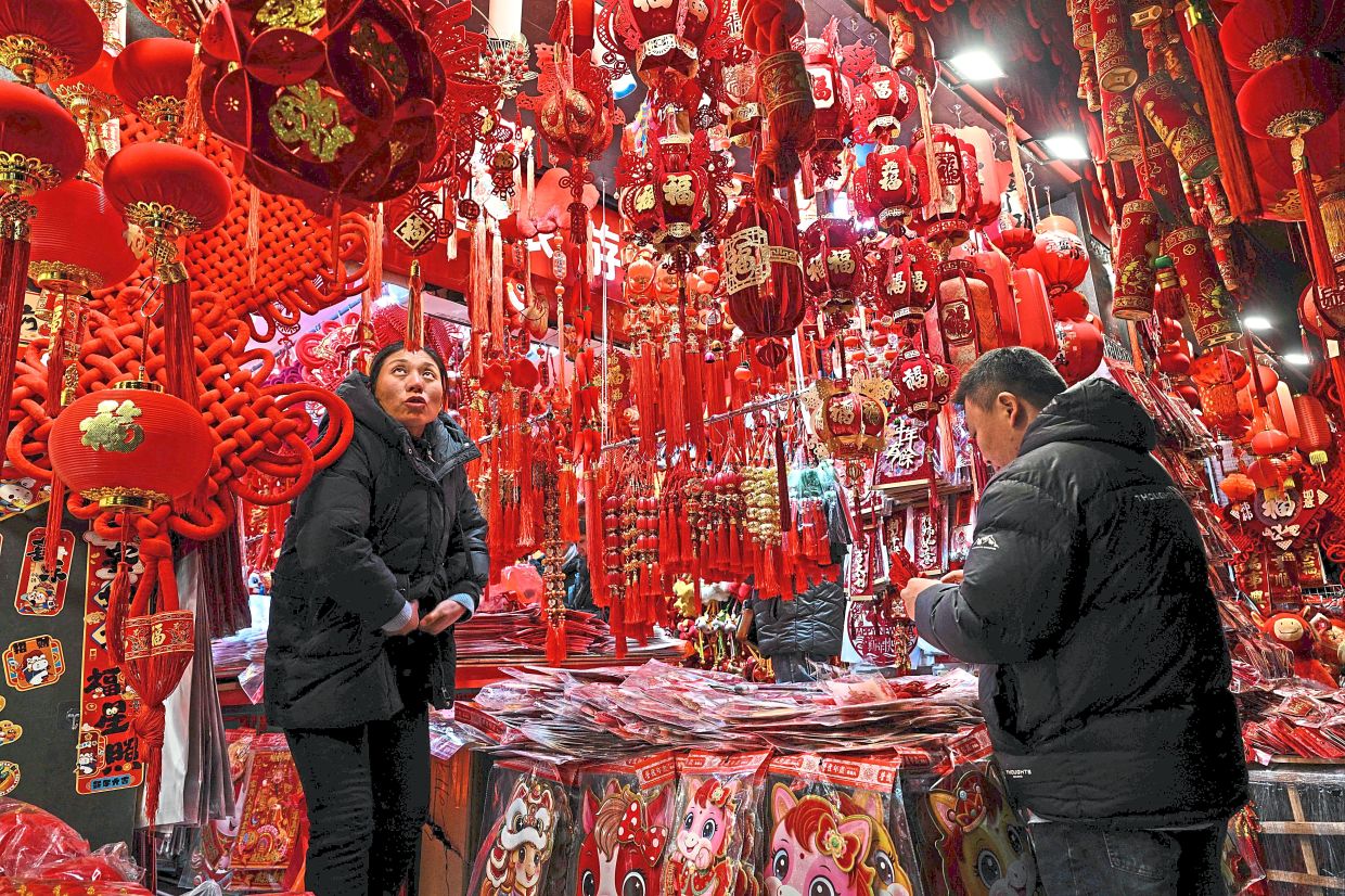 2. A vendor arranging festive decorations for Chinese New Year outside his shop near Yu Garden in Shanghai. — AFP