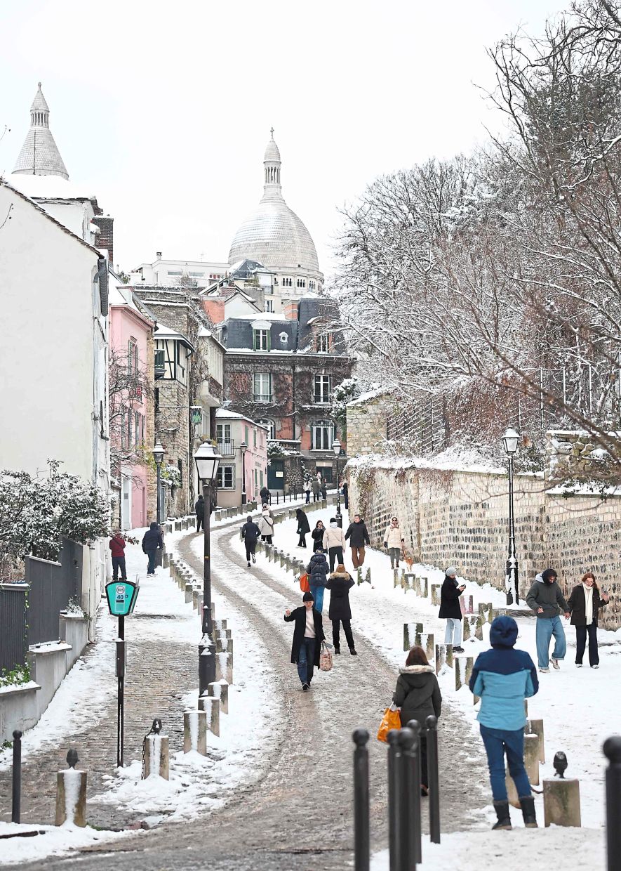 4. Pedestrians navigating snow-covered streets in Montmartre following heavy snowfalls in Paris, France. — AFP