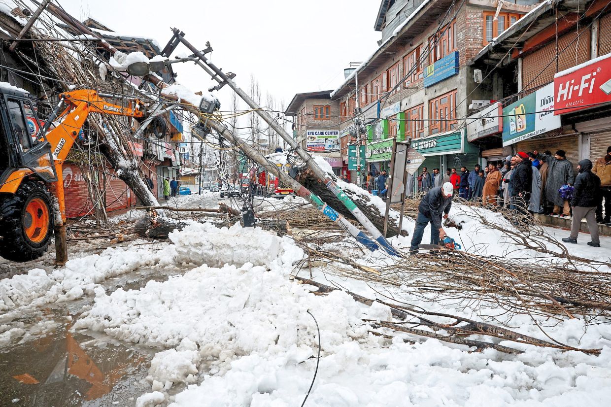2. Workers clearing fallen trees and damaged electric poles after strong winds on the outskirts of Srinagar, Indian Kashmir. — Reuters