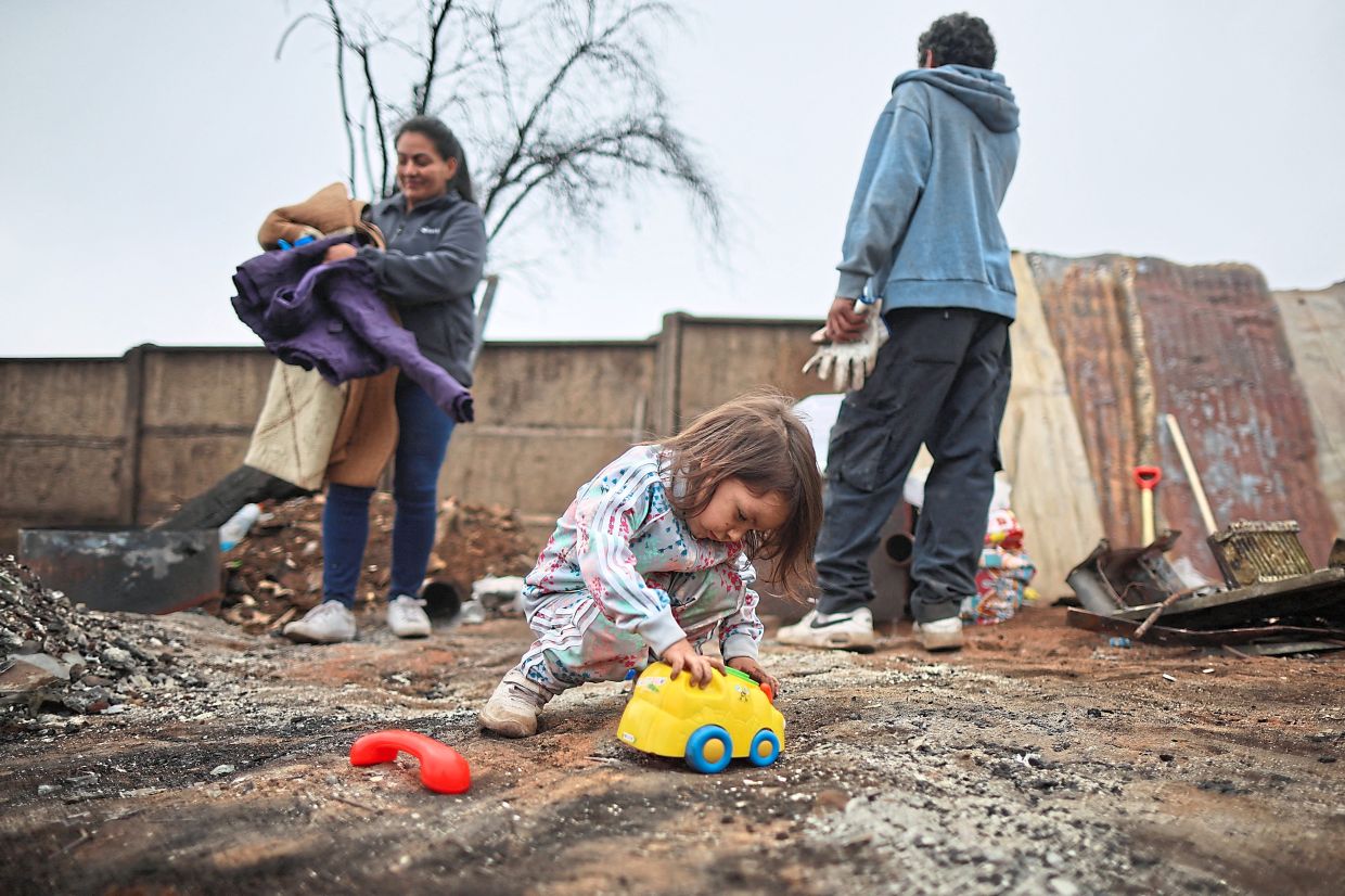 4. A young girl playing with a toy after her home was destroyed by forest fires in Biobio. — Reuters