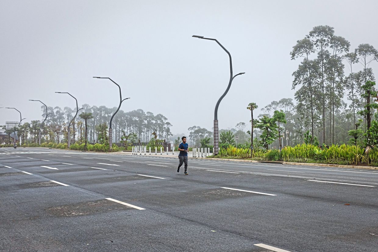 A man jogging along the centre of a multi-lane road by an area of government buildings in Nusantara. — Ulet Ifansasti/The New York Times