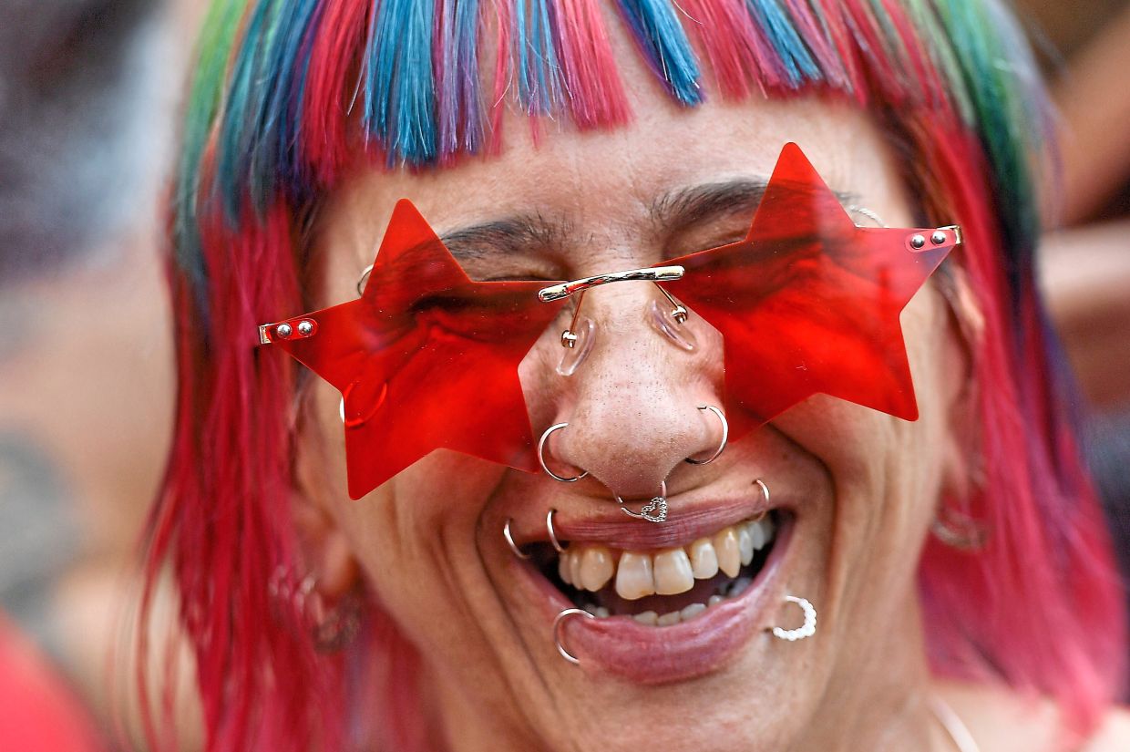 A woman wearing star-shaped glasses smiles during a presidential campaign rally in Sao Paulo, Brazil. — Photos: AP