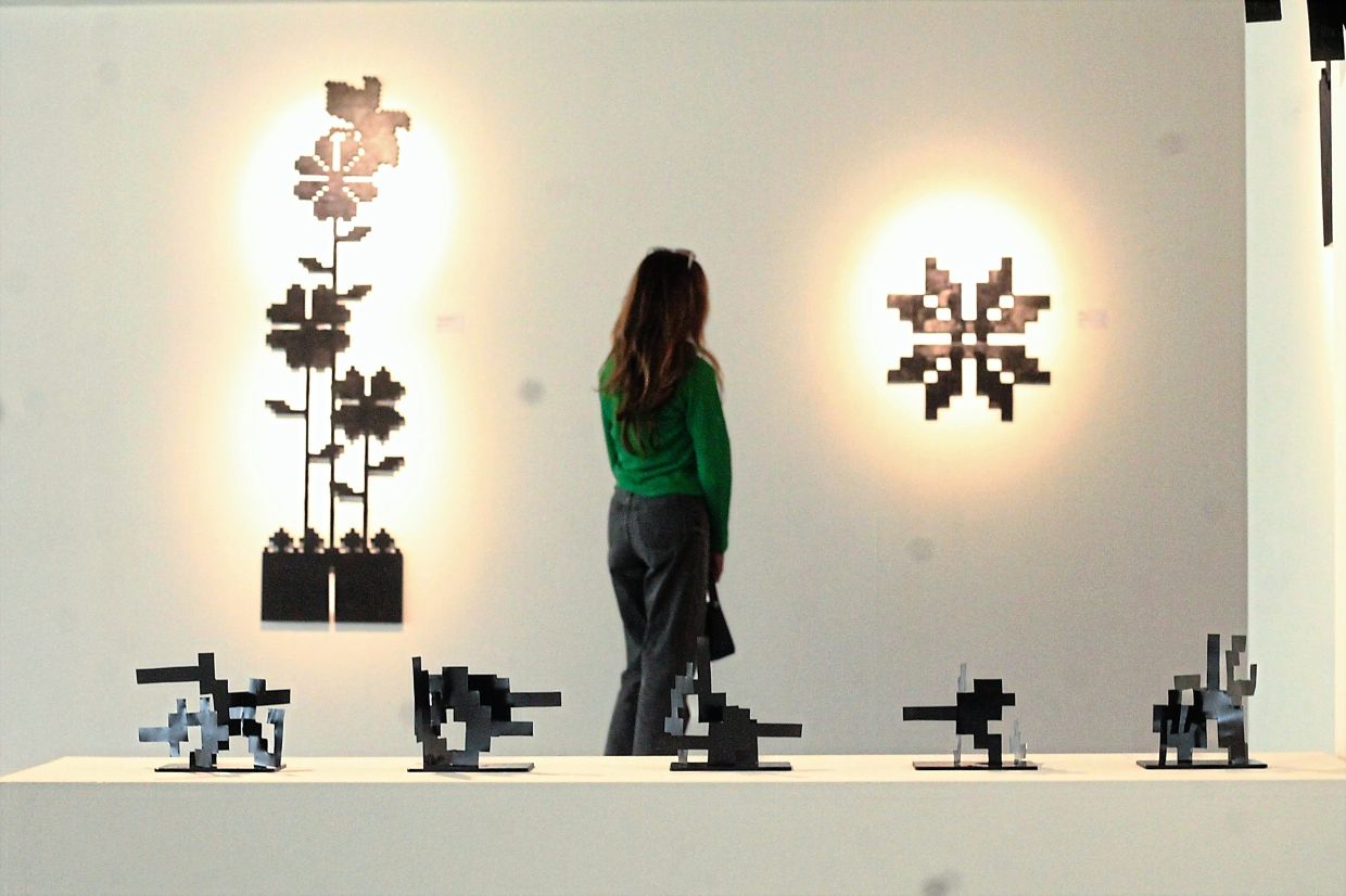 A visitor walks past Faizal's wall-mounted works 'Ria' (left) and 'Metrika' (right), alongside smaller steel sculptures displayed nearby. Photo: The Star/M. Irsyad