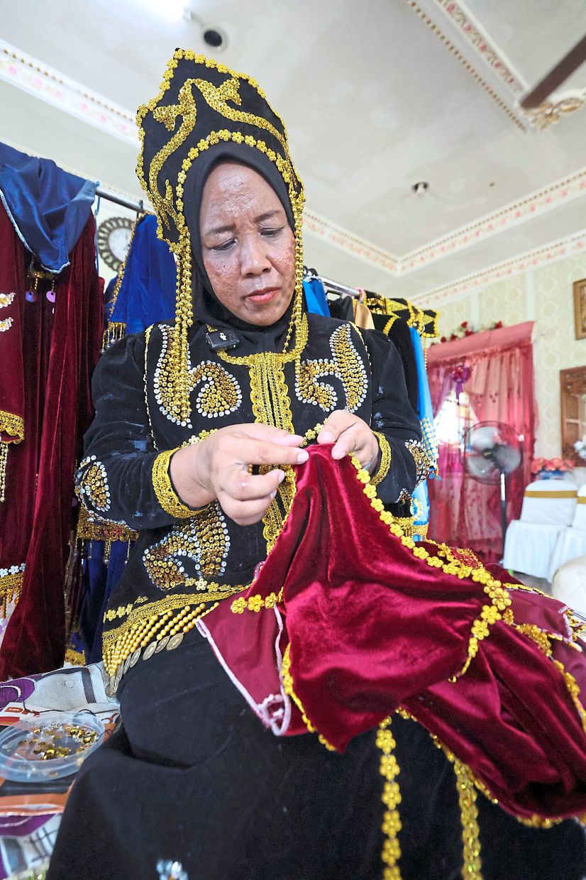 Narimah adding embellishments to an outfit which she produces from home with the help of villagers.