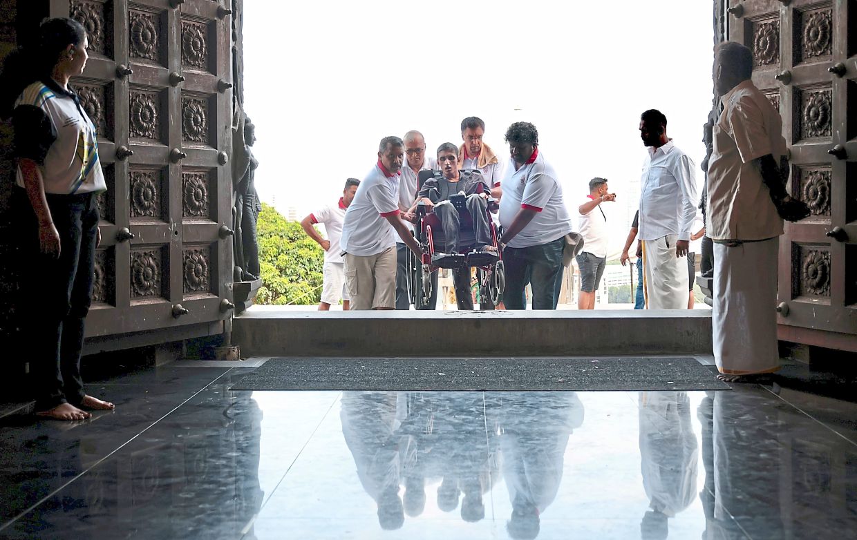 Wheelchair-bound S. Purushotaman being carried into the Waterfall Hilltop Temple by volunteers after he was ferried up the hill in a 4WD vehicle. — ZHAFARAN NASIB/The Star 