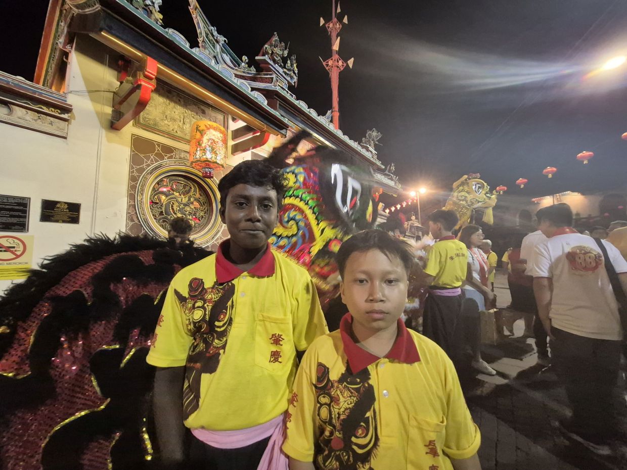GREAT EXPERIENCE...Josiah and Muhammad Izdhihar (right) are happy to be part of Lion Dance troupe to perform during the ceremony.