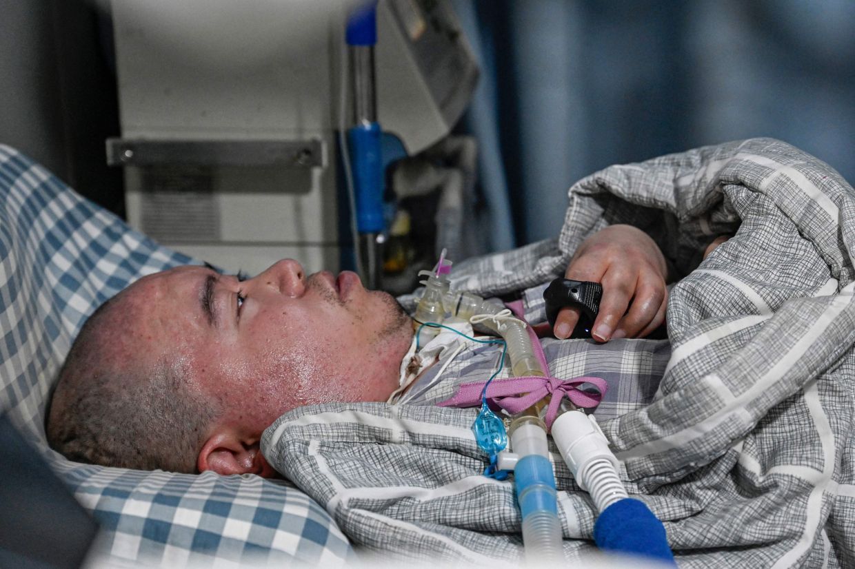 Li Xia, who has Duchenne muscular dystrophy, using a trackball with his fingers to control the computer on a bed at his house in southwestern China's Chongqing municipality.