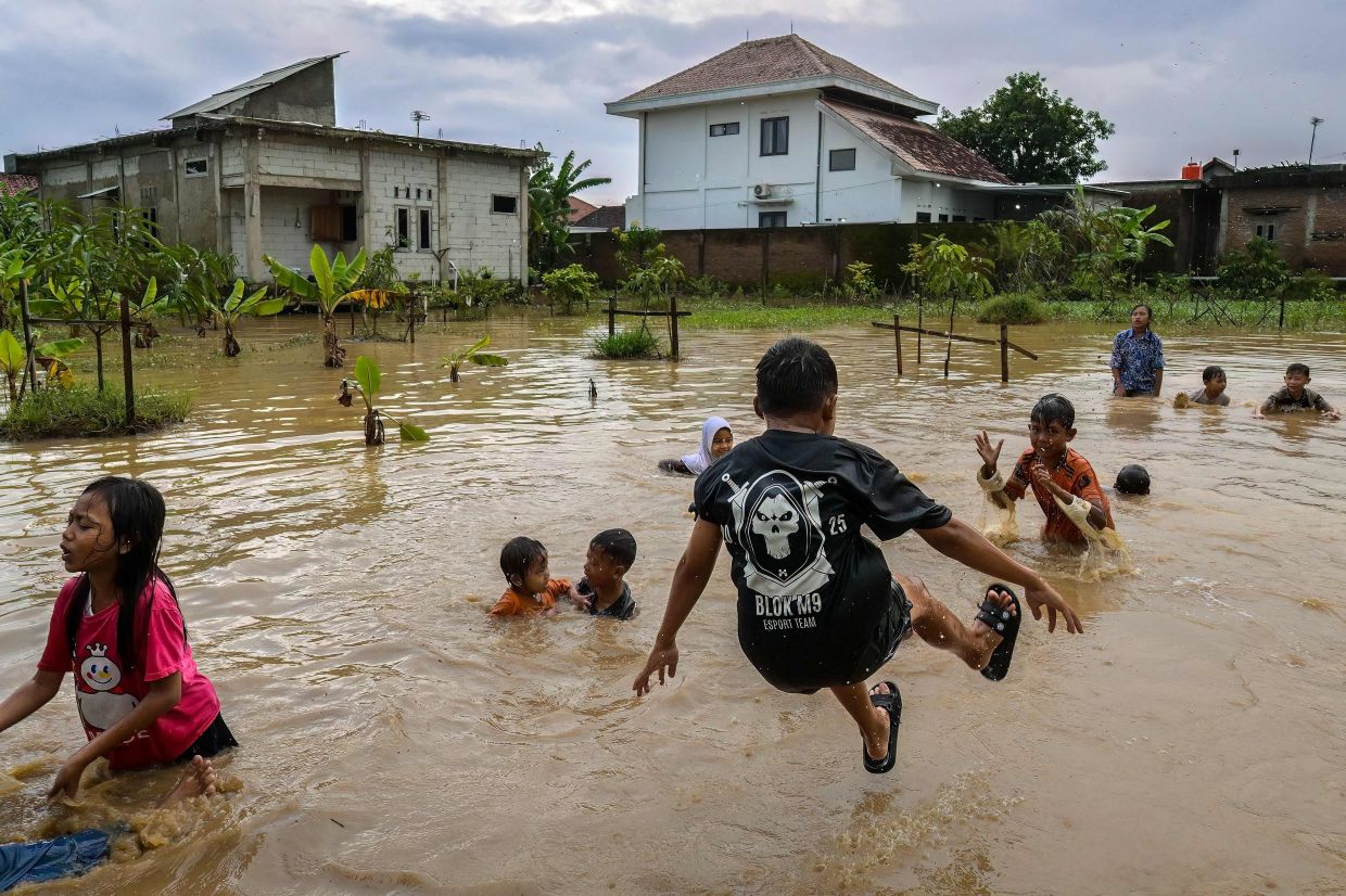 Children playing in water following heavy rainfall near their homes in Cirebon, West Java on Jany 29, 2026. - AFP