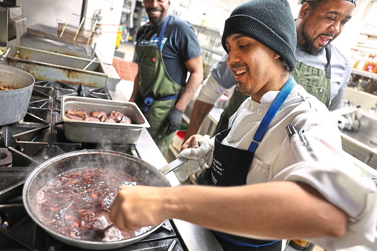 Rosario (front) prepares a wine reduction for a short ribs dish at Burnham Yacht Club.