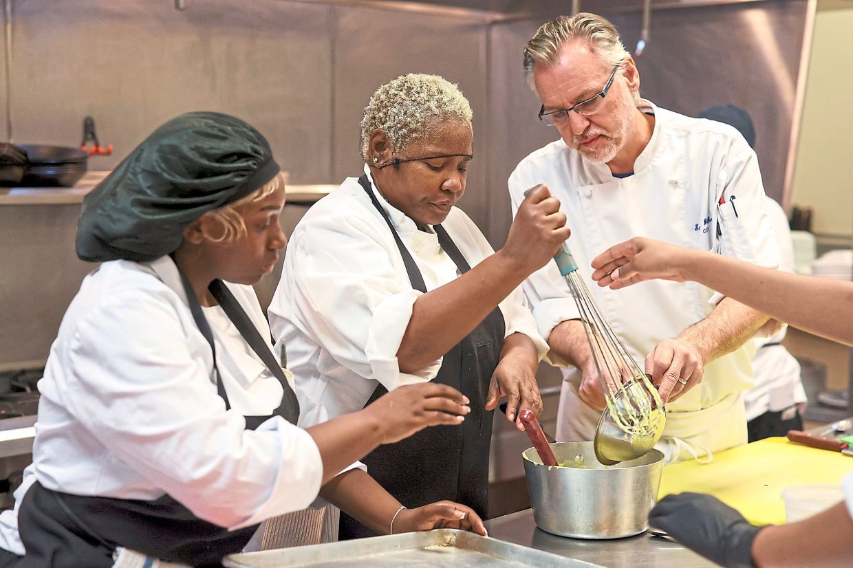 Jones (left) and Wittkopf (right) help Georgia Johnson mix ingredients into a thick cream.