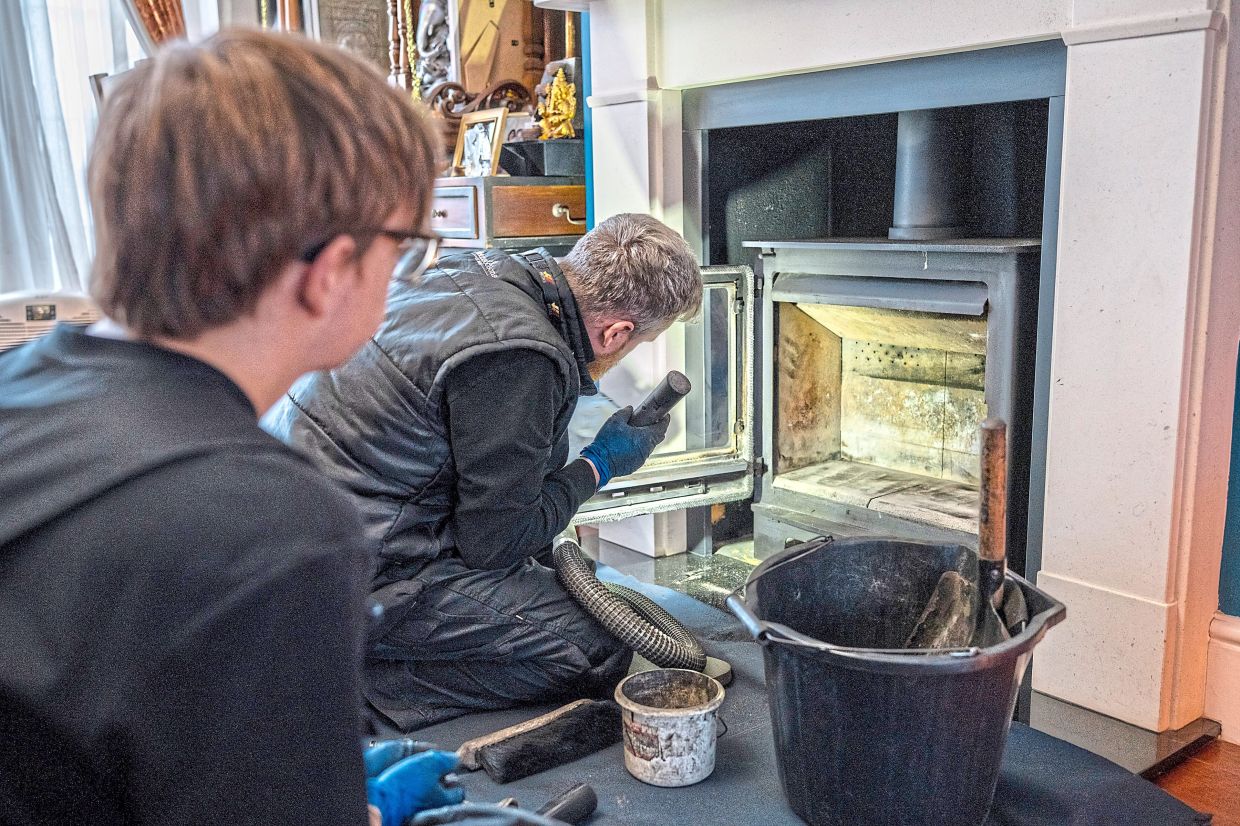 Firkins (right) and apprentice Joslin clean a flue at a London home.