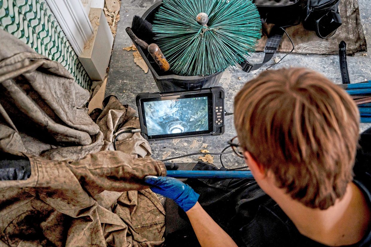 Joslin sees up a chimney’s flue via a camera snaked up from the hearth of the fireplace in a London home.
