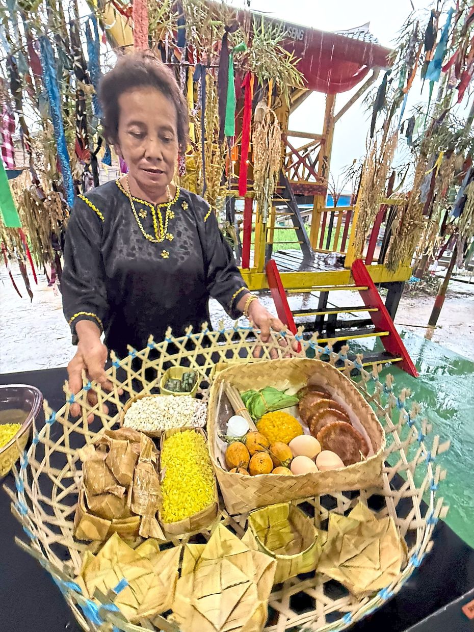Villager Normah Lijih preparing a seraheng for the Kaul Medong with items like ketupat, sirih leaves, glutinous rice and traditional delicacies to offer thanksgiving and seek blessings for the new year.