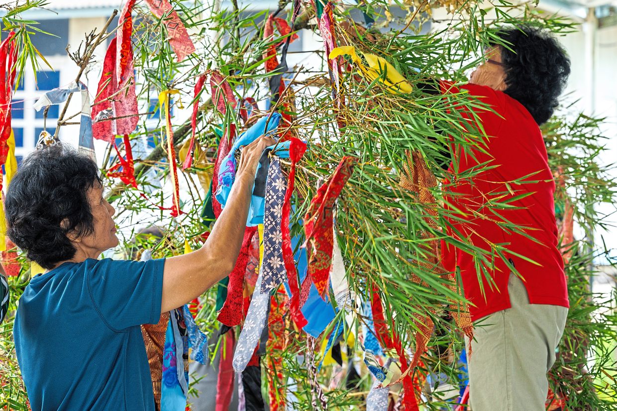 Villagers decorating the seraheng’s bamboo pole with colourful fabric pieces.
