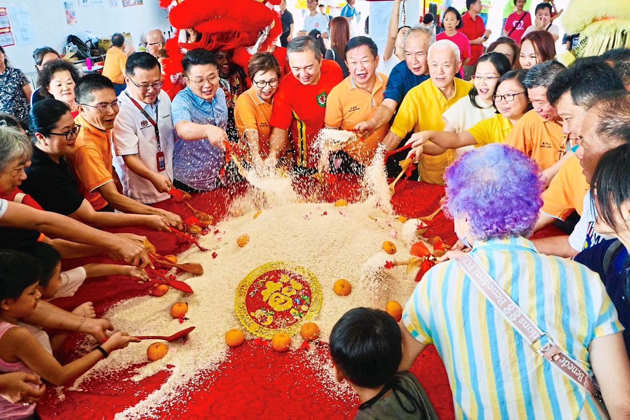 Ng (in red T-shirt) doing a rice mix and toss during a 2024 CNY celebration at a school in his constituency, Kinrara. — Courtesy photo 