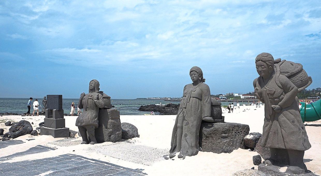 Statues of haenyeo (women free divers) on a beach in Jeju Island.