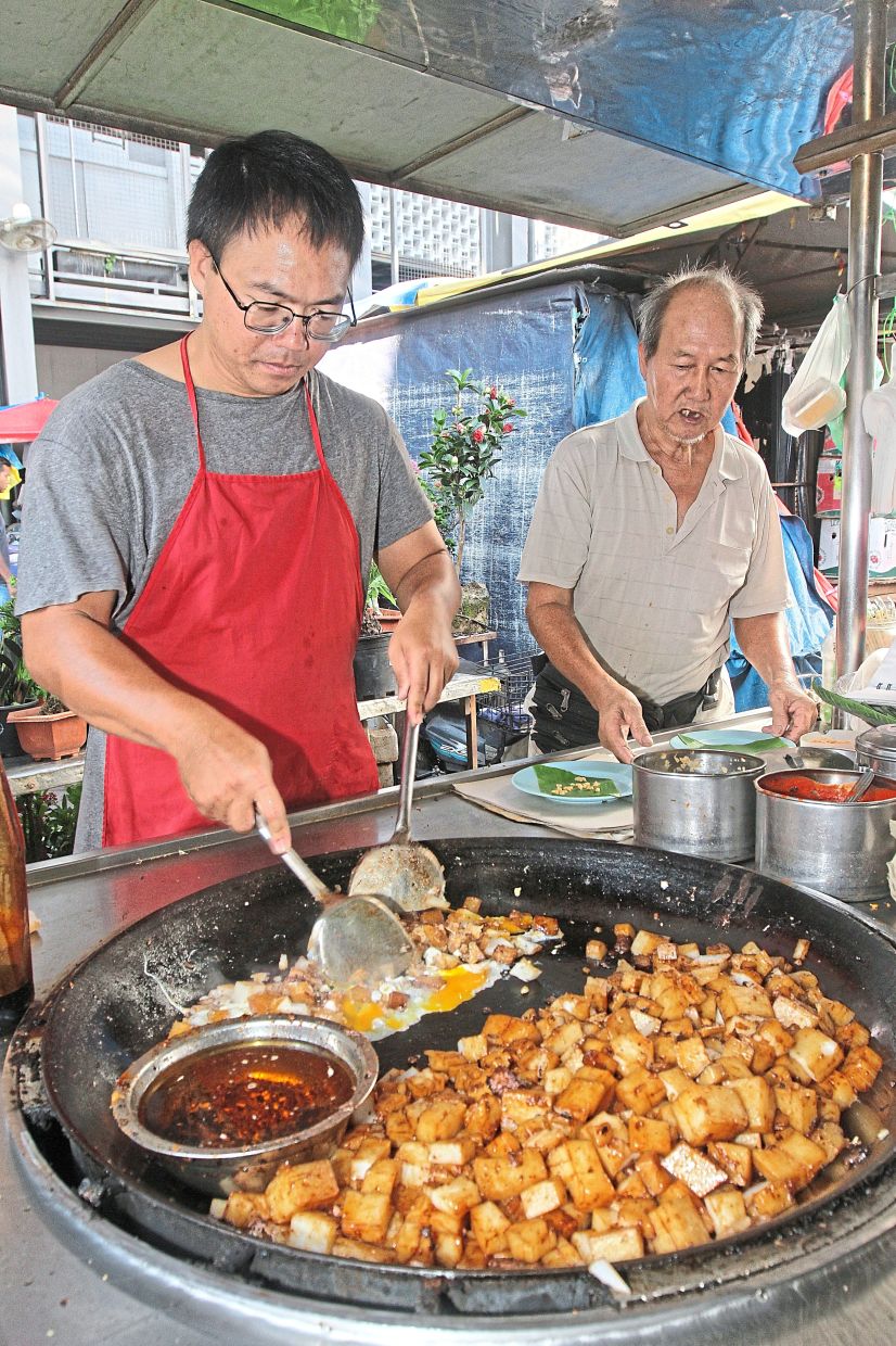 Kan Kar Inn and his father Kan Kwan Yoon at their ‘char kue kak’ stall at Chowrasta Market in George Town. The dish is among Penang’s 10 gazetted heritage food. — LIM BENG TATT/The Star