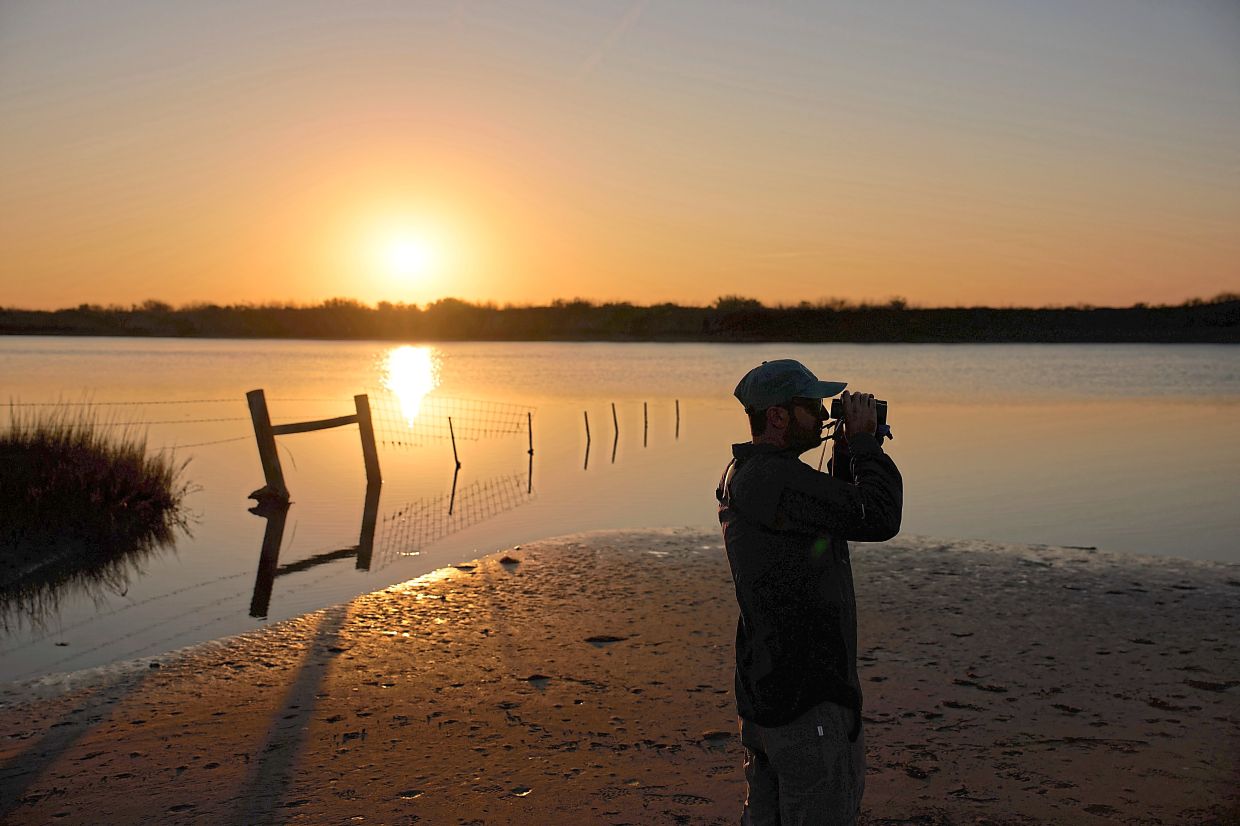 Crouch looks through binoculars as the sun rises at the sanctuary.