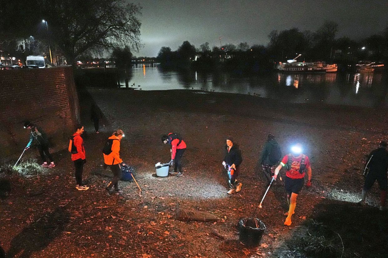 Group members collect litter from the riverbank.
