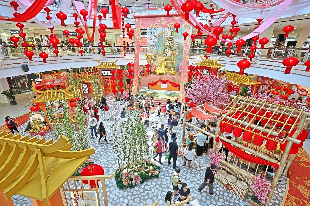 Shoppers exploring Queensbay Mall’s vast and symbolic ‘Spring Returns, Joy Unbound’ festive landscape, featuring a towering scroll and cutesy horses, among other classic cultural imagery.