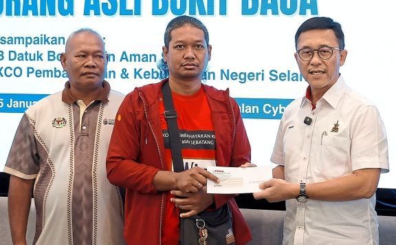 Borhan presenting a cheque to a villager at the Cyber Valley sales gallery as Jalil (left) looks on.