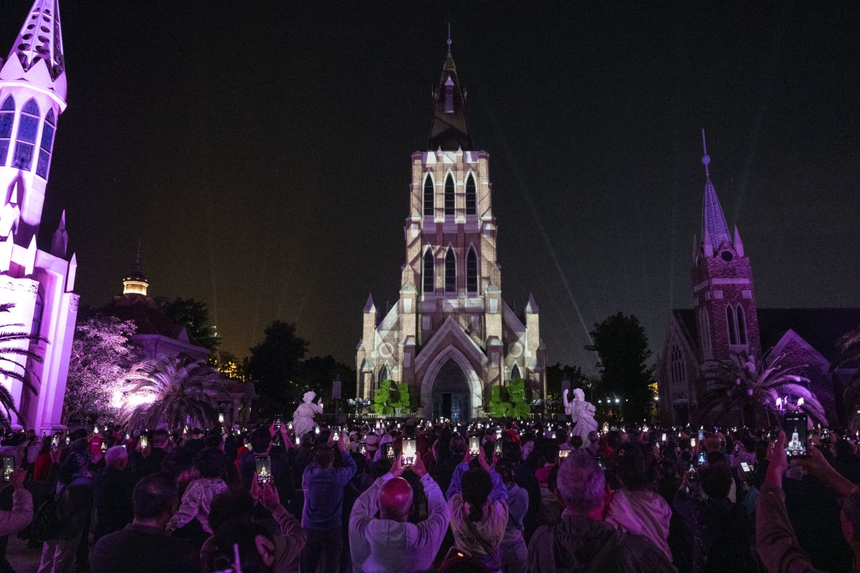 People watch a sound-and-light show projected on a fake cathedral, built as an Instagram-able setting for wedding photos, on the man-made development of Ocean Flower Island, in the South China Sea just off Hainan, on Jan. 1, 2026. — Photo: Gilles Sabrie/The New York Times