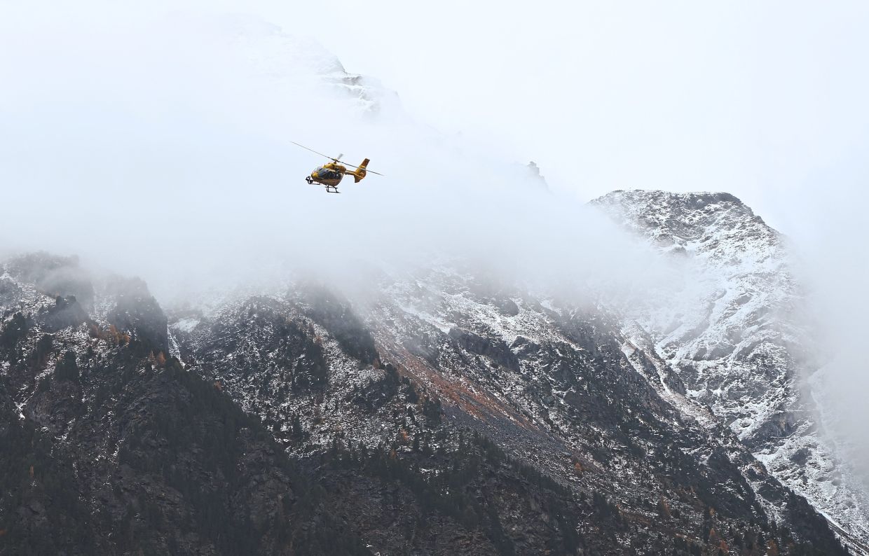A mountain rescue helicopter flies over snow-covered Ortler Mountains in South Tyrol. — KARL-JOSEF HILDENBRAND/dpa