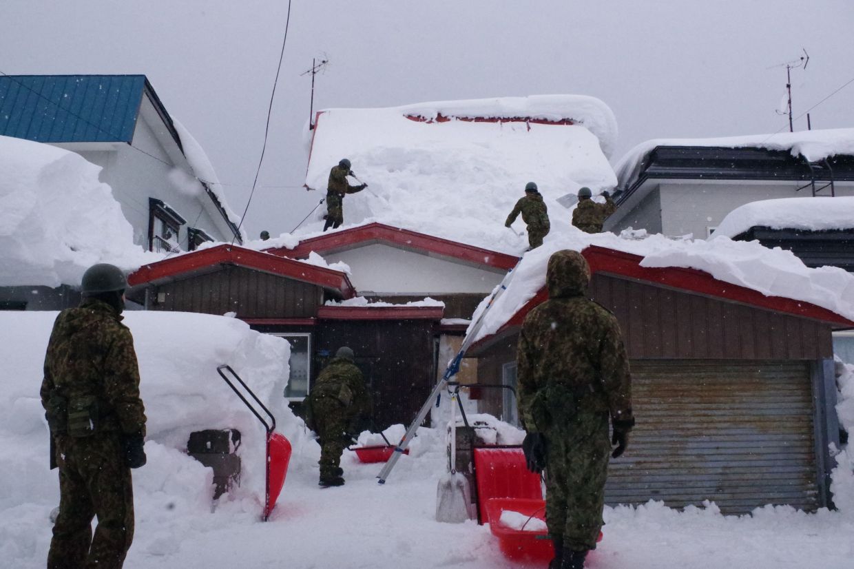 Members of the Japan Ground Self-Defence Force's 5th Infantry Regiment, stationed in Aomori Prefecture, carrying out snow removal work in a town within Aomori Prefecture. Sustained snow since late January has buried northern communities like Aomori under drifts of around two metres that left residents struggling to leave home and forced schools and businesses to close. - AFP