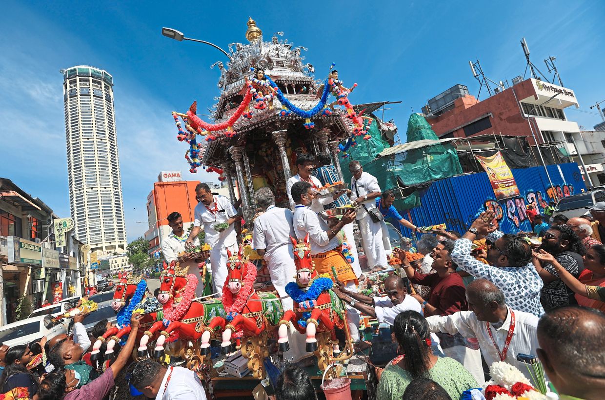 Devotees making offerings to Lord Muruga on the silver chariot during the procession along Jalan Datuk Keramat.