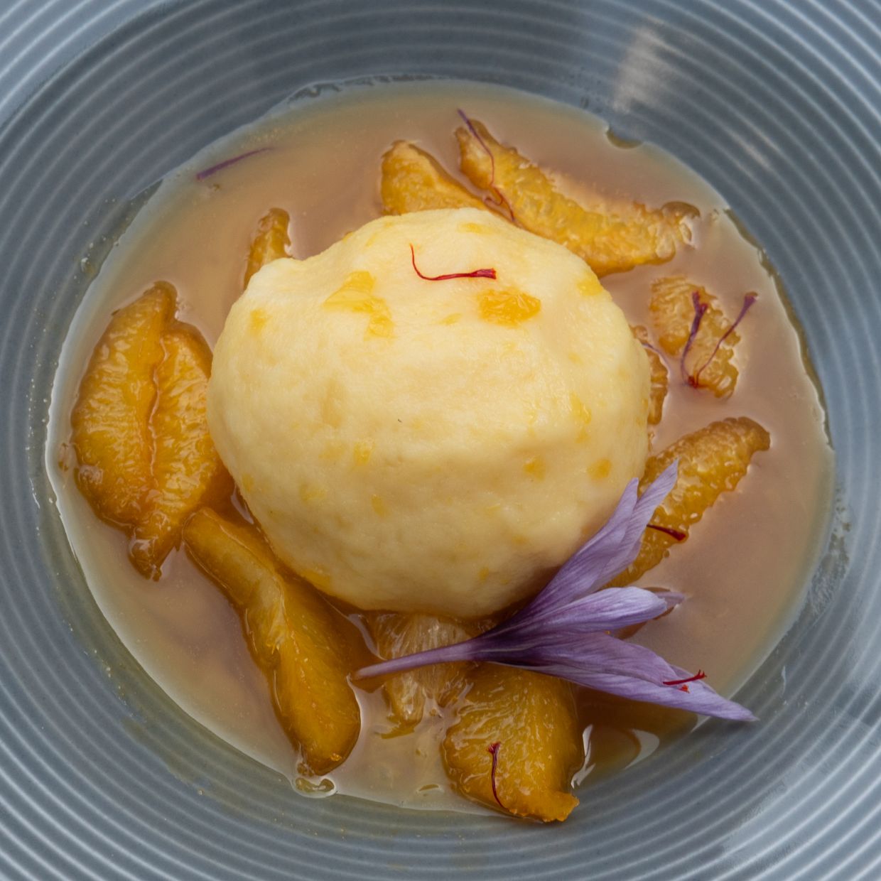 Orange fruit salad with saffron and a warm potato dumpling. — Photo: Andreas Drouve/dpa