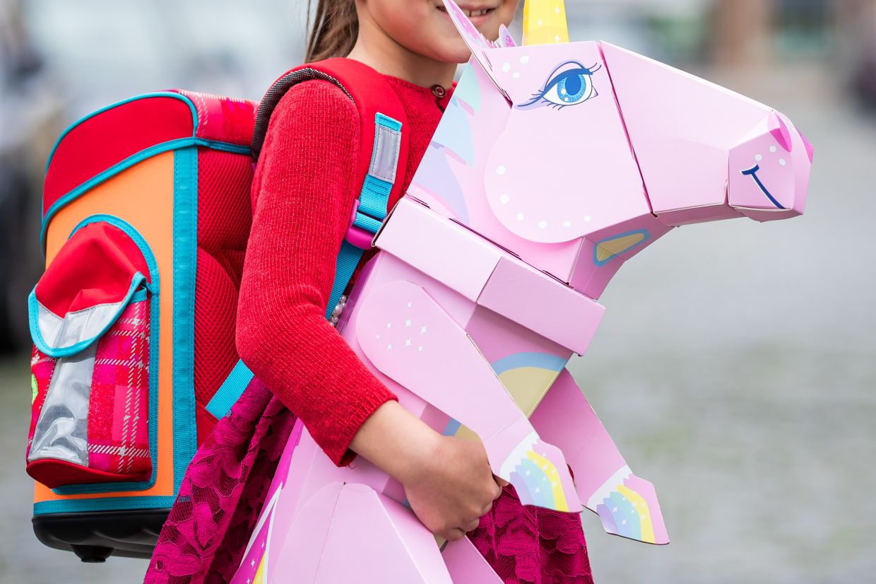 A first-grader stands with her school bag and unicorn Schultüte (school cone), often packed with gifts and sweets and traditionally given to children on their first day of primary school in Germany. — Photo: Moritz Frankenberg/dpa
