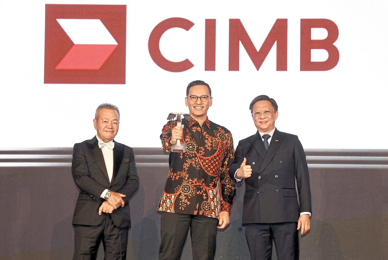 CIMB group chief brand and marketing officer Toni Darusman (middle) holds up silver award for the Banking, Investment and Insurance as SMG group CEO Chan Seng Fatt (right) and Mun look on.