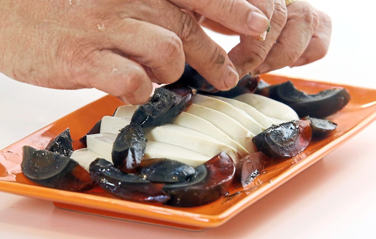 Place the sliced tofu on a serving dish and arrange century egg wedges on and around it.