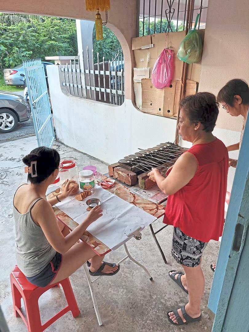 Ng (seated from left) is with her family in Ipoh making love letters cookies for Chinese New Year. - COURTESY OF NG.