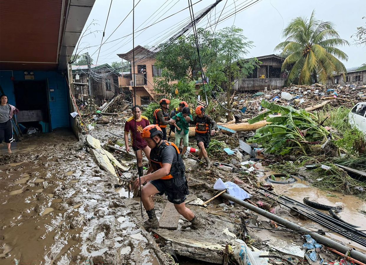 Rescuers evacuaing a woman after Tropical Storm Penha hit the area in Iligan, Lanao del Norte province on Feb 6, 2026. - AFP