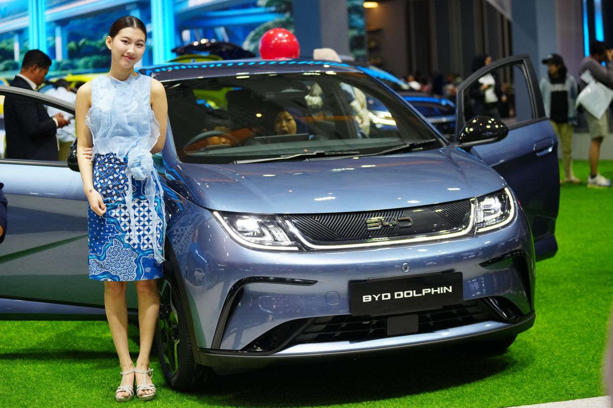 A model stands near a BYD Dolphin, an electric vehicle from Chinese automaker BYD, during the Indonesian International Motor Show in Jakarta, Indonesia. -- AP Photo/Tatan Syuflana