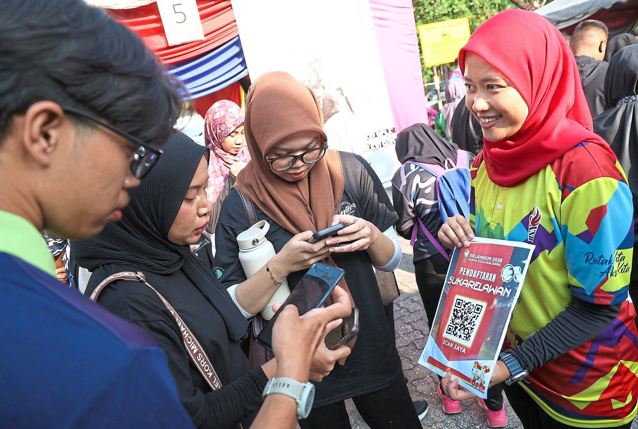 Volunteers scanning a QR code to register as volunteers for the upcoming Games.