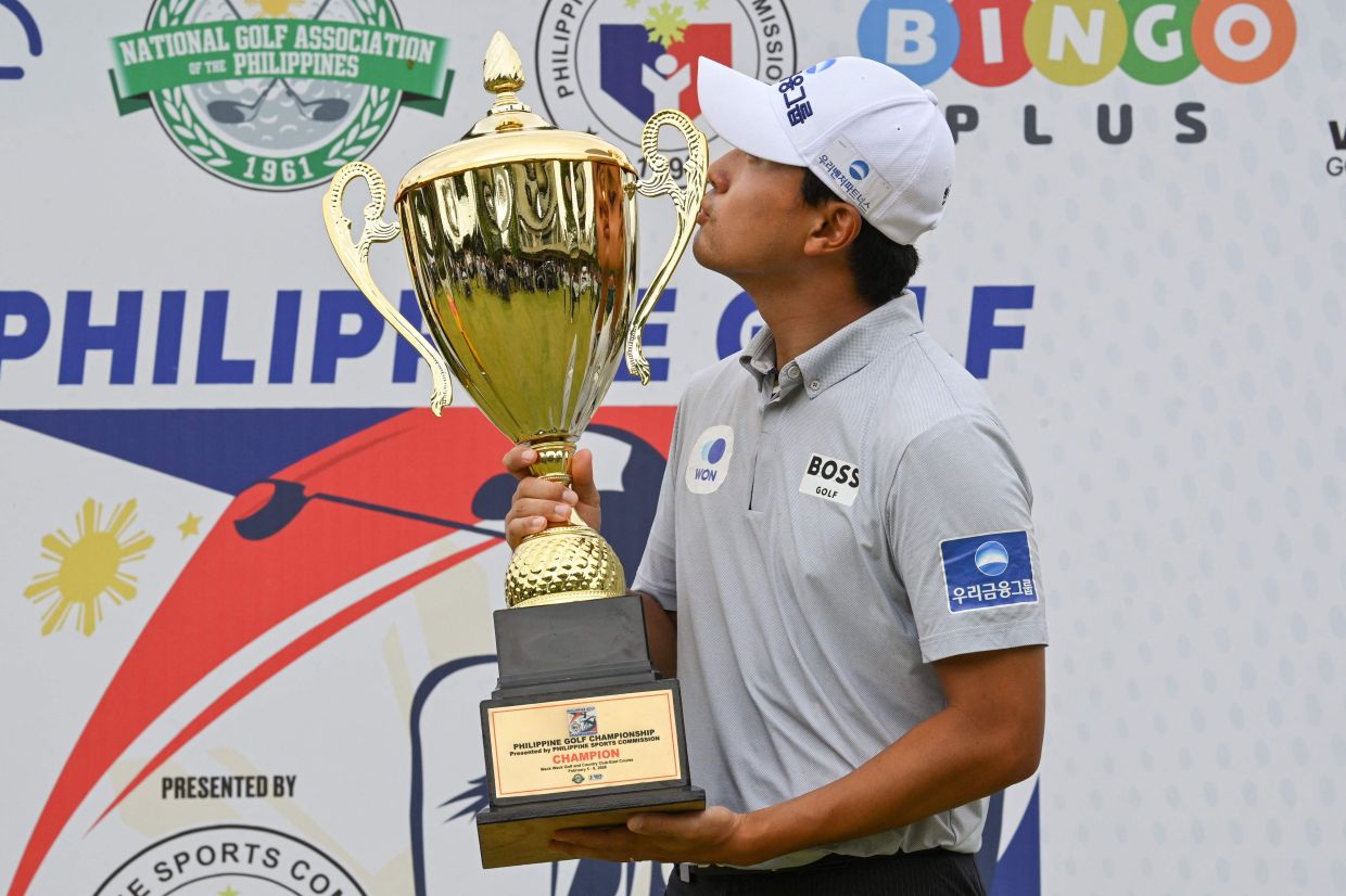 Cho Woo-young of South Korea kisses the trophy after winning the Philippines Golf Championship at Wack Wack Golf and Country Club in Manila. -- Photo by Ted ALJIBE / AFP