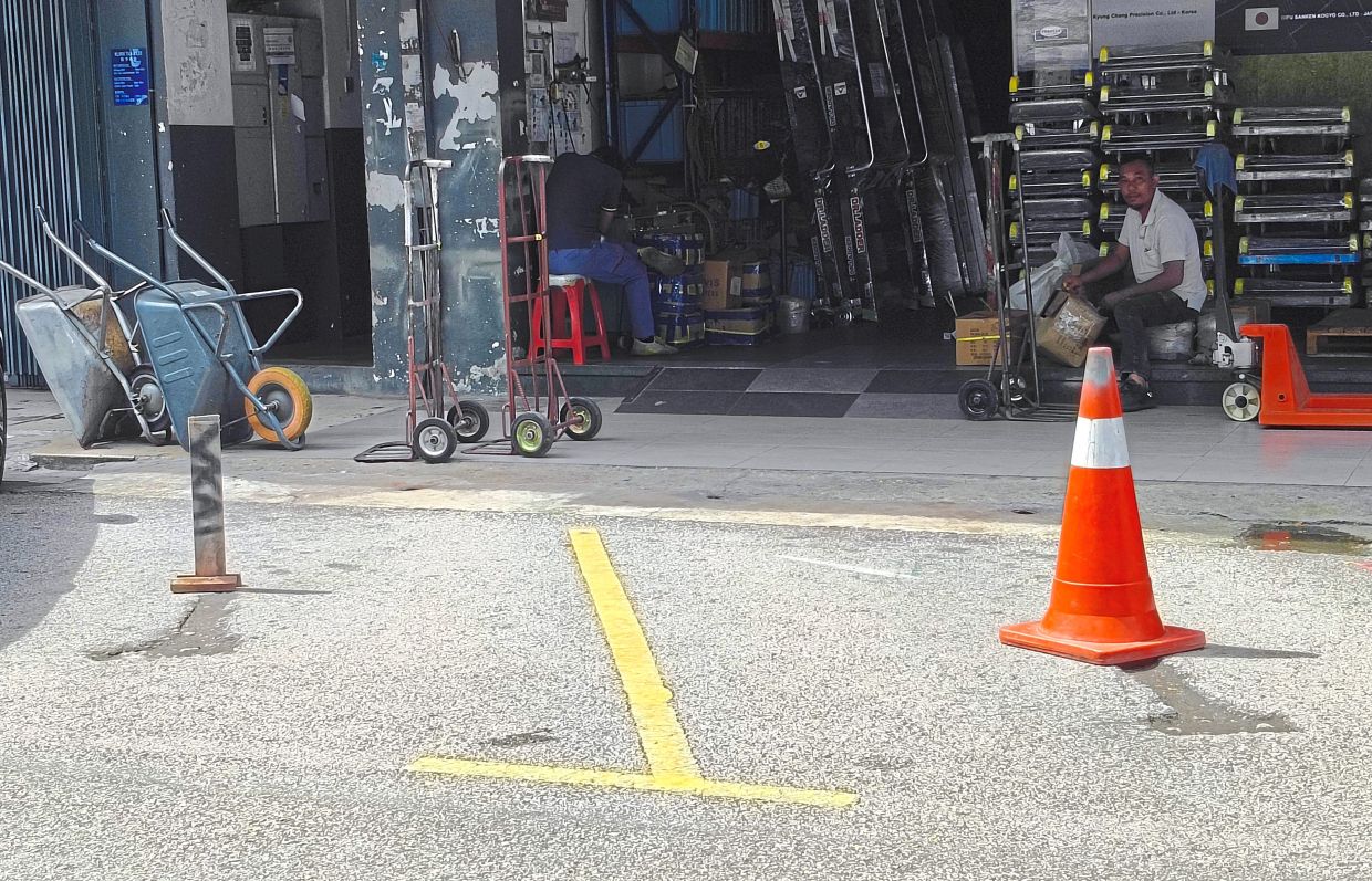 A traffic cone and pole placed to reserve parking lots in front of business premises in Kuchai Entrepreneurs Park.