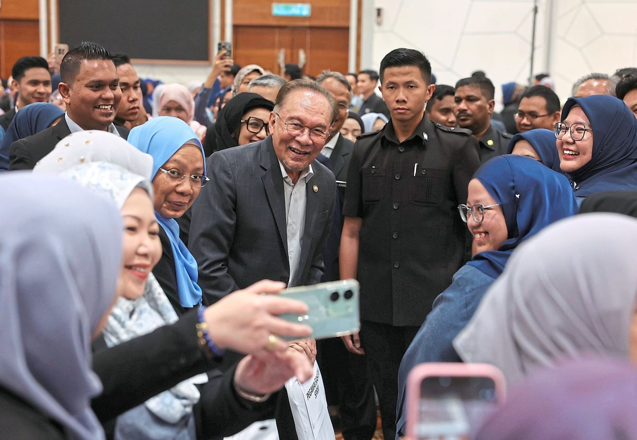 Smile, everyone: Anwar taking a photo with employees at the National Unity Ministry’s monthly assemblyin Putrajaya.— Bernama