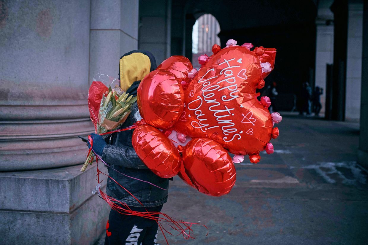 A man walks holding flowers and balloons on Valentine's Day, Friday, Feb. 14, 2025, in New York. — AP/Andres Kudacki