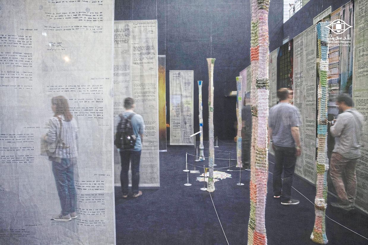 Visitors walk through Xeem’s installation at NAG, a replica of her residency apartment in Japan, built from knitted pillars and printed fabric panels. Photo: Balai Seni Negara