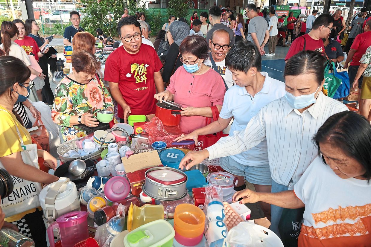 Ng (in red T-shirt) watching as people check out a variety of pre-loved items at the Air Itam Free Market 5.0 event. — Photos: ZHAFARAN NASIB/The Star