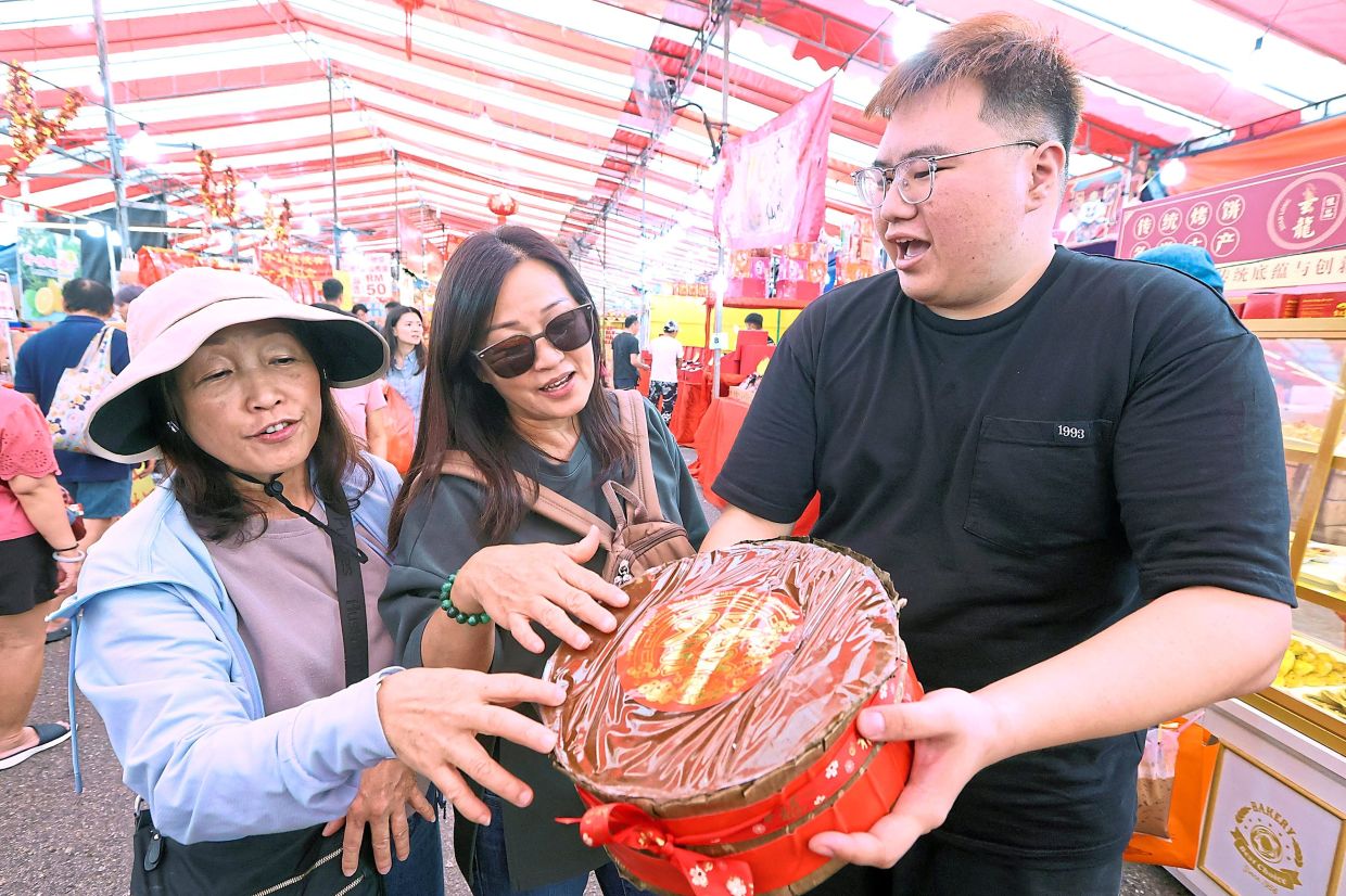 Ng (right) showing customers a ‘nian gao’, which is also known as ‘kuih bakul’ in Malaysia. — THOMAS YONG/The Star