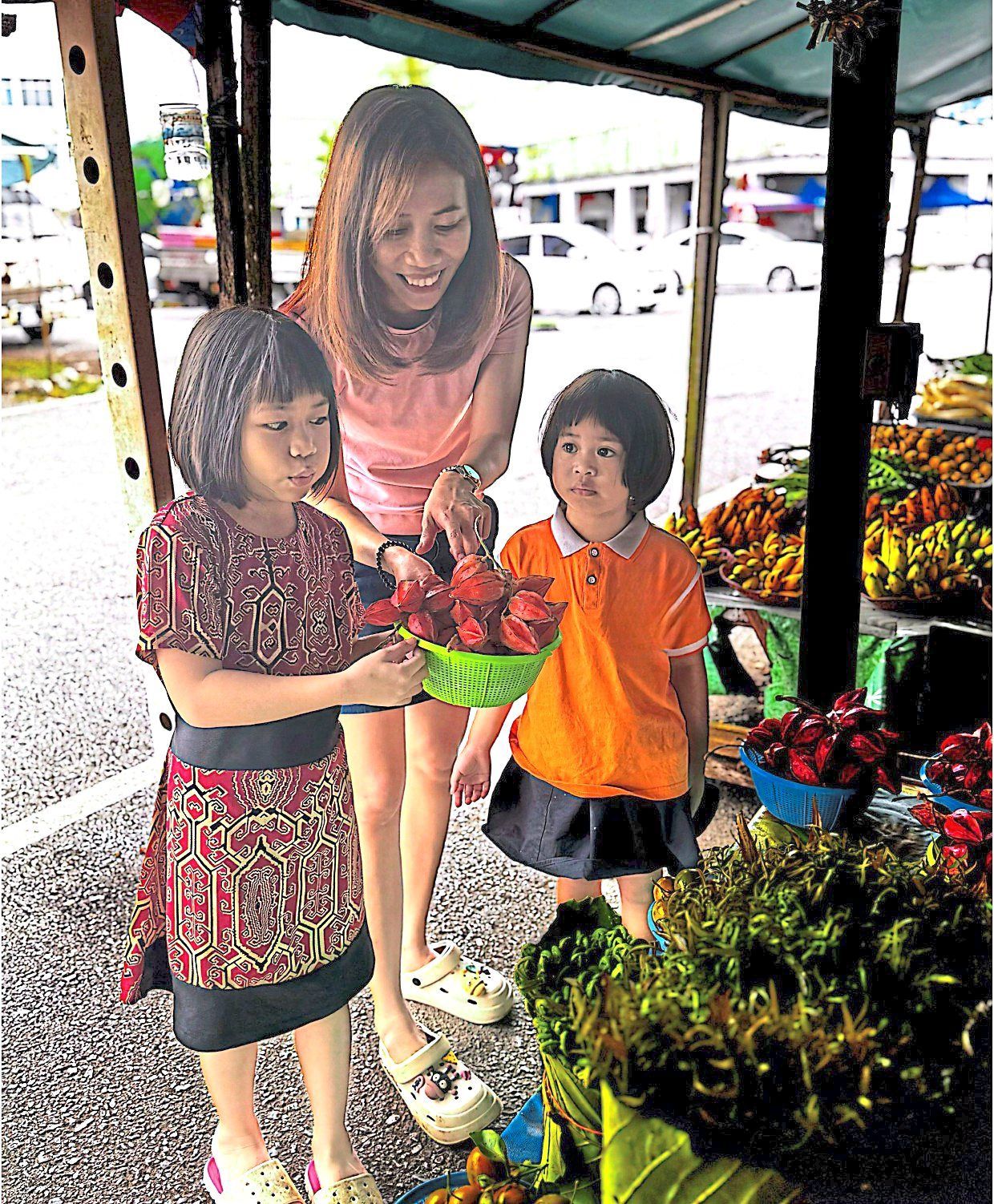 Safphia brings her children, Eleanor Yeow (left) and Daisy Yeow (right) to the market to expose them to a variety of local fruits. Photo: Safphia Judin