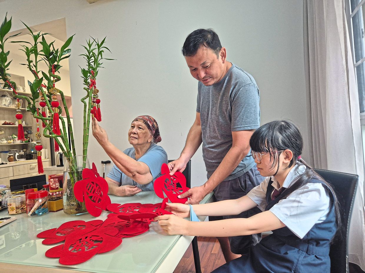 Tan (left) together with her son Lee (centre) and granddaughter Tokiho decorate their home in time for the upcoming Chinese New Year. Photo: The Star/Sheela Chandran