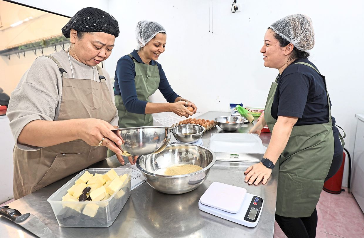 Dina (right) guiding Rahmawati (left) and Parveender as they prepare the flour and ingredients to make brownies.
