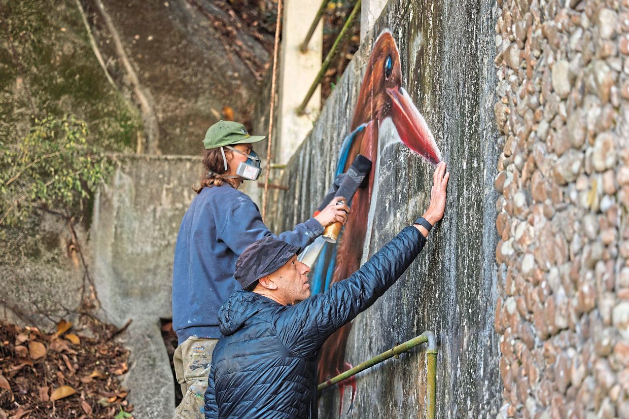Making a mark: Johnson-Hill (front) looking at a white-throated kingfisher mural being painted by Aspire.—AP